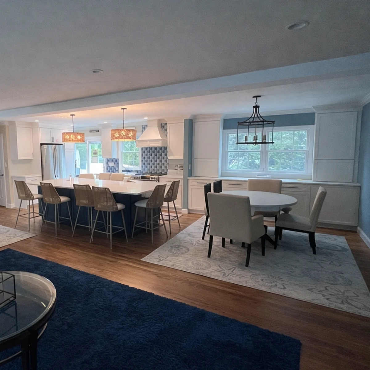Open-plan white kitchen with blue island by Iron Mike Construction and Design