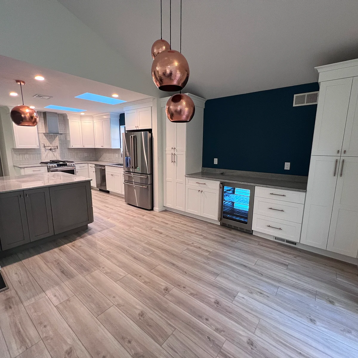 White kitchen with gray island and copper pendants